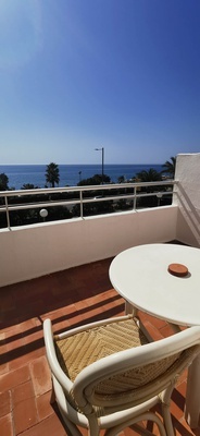 a white table and chair on a balcony overlooking the ocean