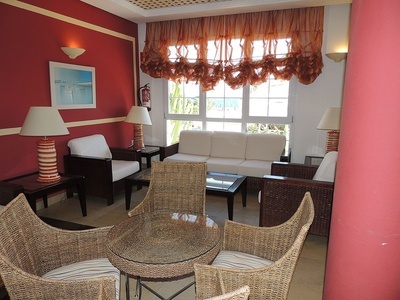 una sala de estar con muebles de mimbre y una mesa de vidrio - 