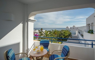 a balcony with two chairs and a table with a pitcher of orange juice on it