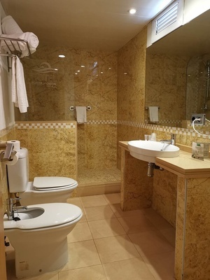 a bathroom with two toilets and a sink with the word hotel on the wall