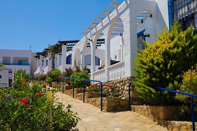 Hotel El Puntazo: fachada blanca con arcos y vegetación exuberante bajo cielo azul. - 