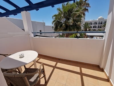 a balcony with a table and chairs and palm trees in the background