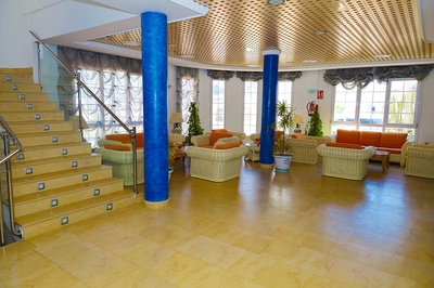 Modern hotel lobby El Puntazo con sofás naranjas y escaleras de mármol. - 