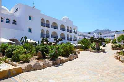 Hotel El Puntazo, resort blanco con patios ajardinados y piscinas. - 