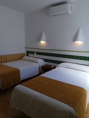a hotel room with two beds and a wall mounted air conditioner