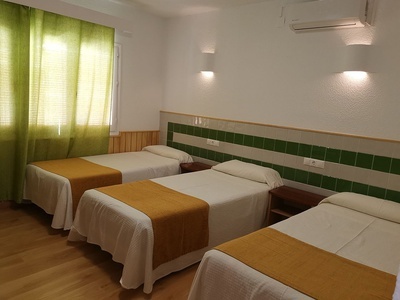 three beds in a hotel room with green curtains