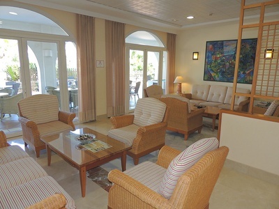 una sala de estar con muebles de mimbre y una mesa de vidrio - 