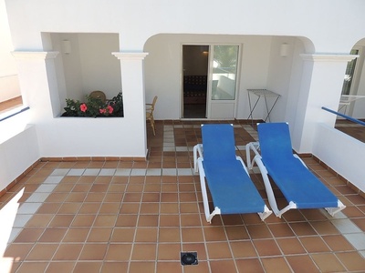 two blue lounge chairs sit on a tiled balcony