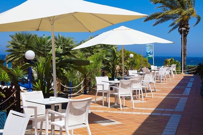 Terraza de restaurante El Puntazo con vistas al mar y palmeras. - 