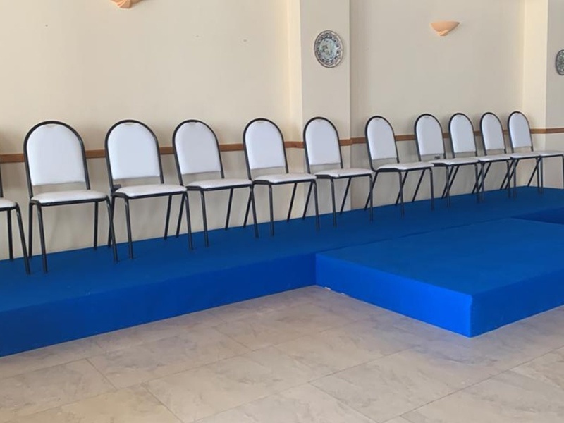 una fila de sillas blancas sobre un piso azul