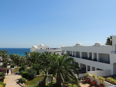 un edificio blanco con palmeras y vistas al océano