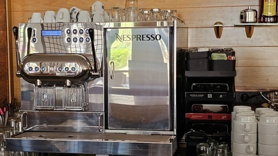 a stainless steel nespresso machine sits next to a stack of cups - 