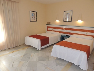 a hotel room with two beds and two pictures on the wall