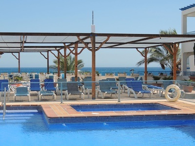 una piscina rodeada de sillas y toldos con vistas al océano - 
