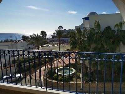a view of the ocean from a balcony with a hotel in the background