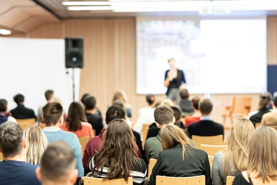 un grupo de personas se sienta en sillas en una sala de conferencias
