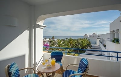 a balcony with two chairs and a table with a pitcher of orange juice on it
