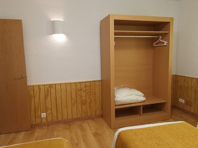 a bedroom with two beds and a wooden wardrobe