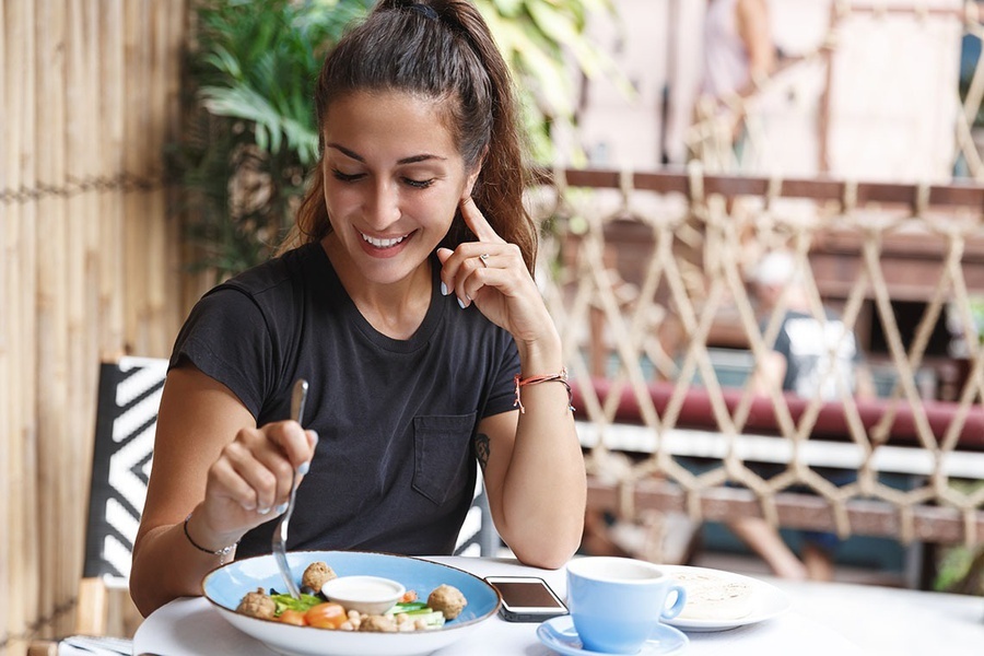 una mujer está sentada en una mesa comiendo y hablando por teléfono