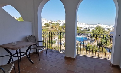 a balcony with a table and chairs overlooking a pool