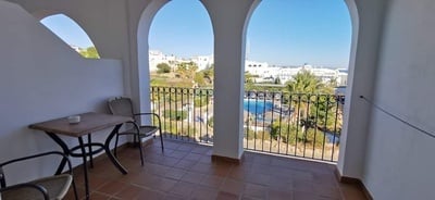 a balcony with a table and chairs overlooking a pool