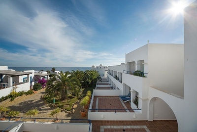 un edificio blanco con vistas al océano y palmeras