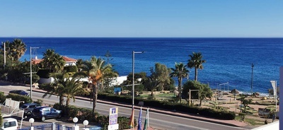 una vista del océano desde una carretera con un letrero que dice ' alquiler de apartamentos '