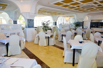 Elegante comedor en El Puntazo con mesas vestidas de blanco y sillas cubiertas. - 
