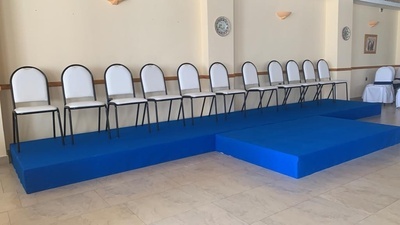 una fila de sillas blancas y un escenario azul - 