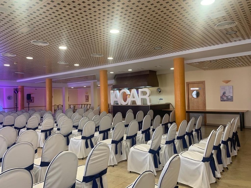 una sala llena de sillas blancas y azules con la palabra acar en el fondo