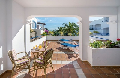 a balcony with a table and chairs and a view of the ocean