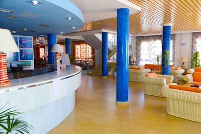 Recepción y sala de estar de El Puntazo con sofás naranjas y muebles de mimbre. - 