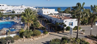 an aerial view of a hotel with a pool and palm trees