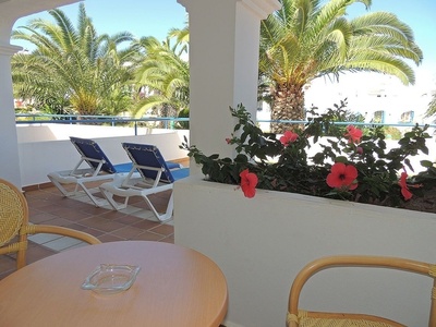 una mesa y sillas en una terraza con flores y palmeras