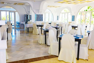 Salón de eventos en El Puntazo con mesas vestidas y sillas cubiertas, listo para recibir a sus invitados. - 