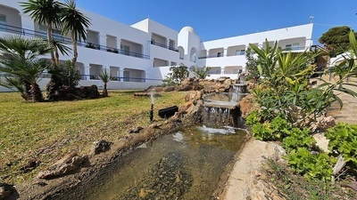 a white building with a waterfall in front of it - 