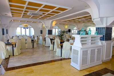 Restaurante El Puntazo con mesas cubiertas y decoraciones en blanco. - 