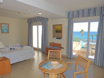 a hotel room with a table and chairs and a view of the ocean