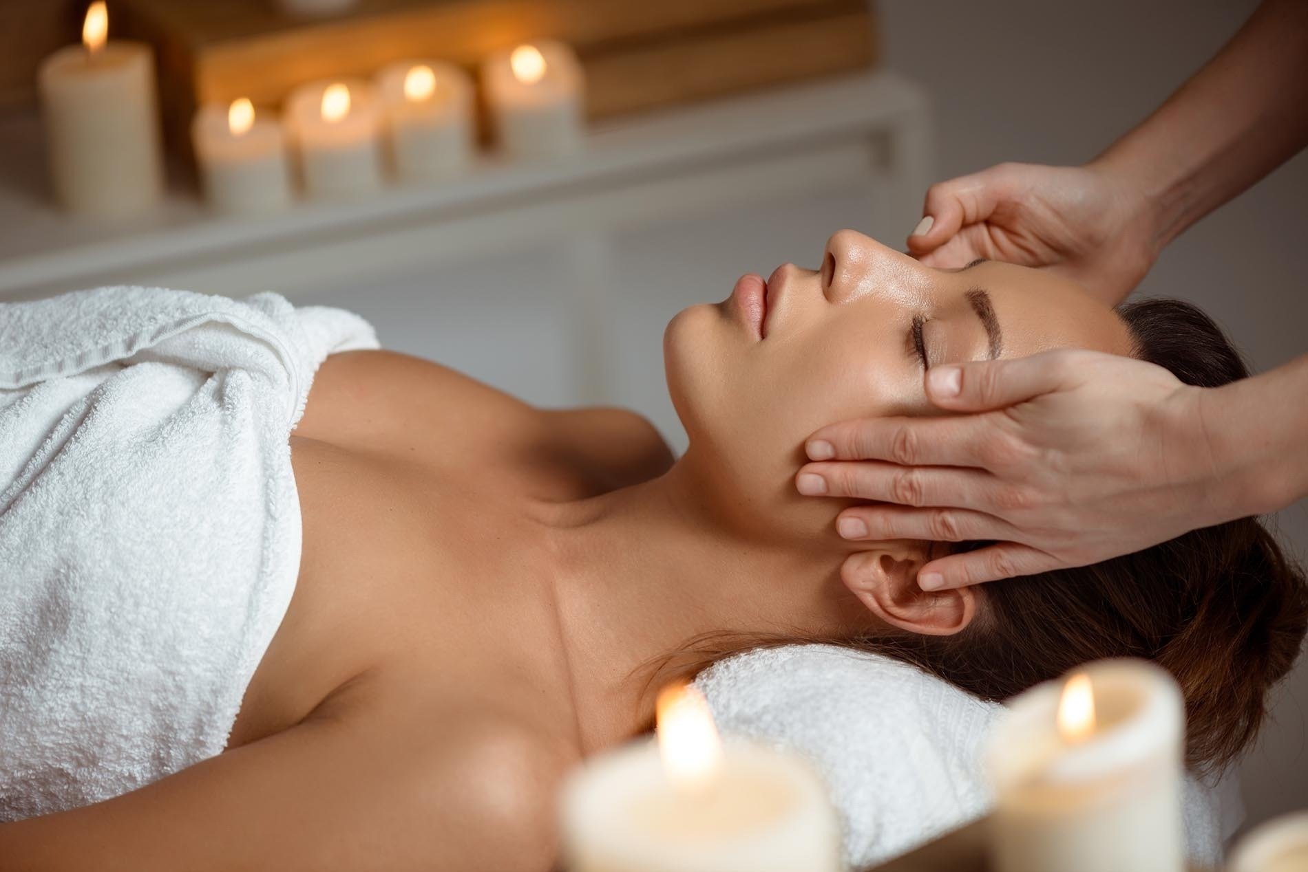 a woman is getting a head massage with candles in the background