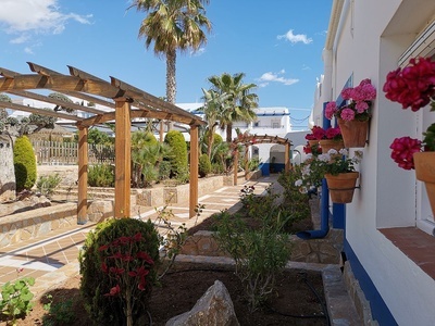 un patio con flores en macetas y una pergola de madera - 