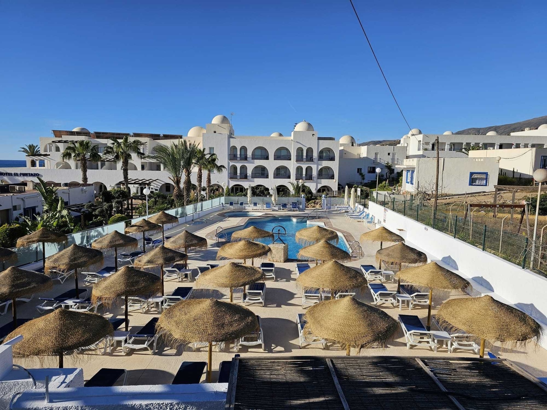 a swimming pool with umbrellas and chairs in front of a hotel