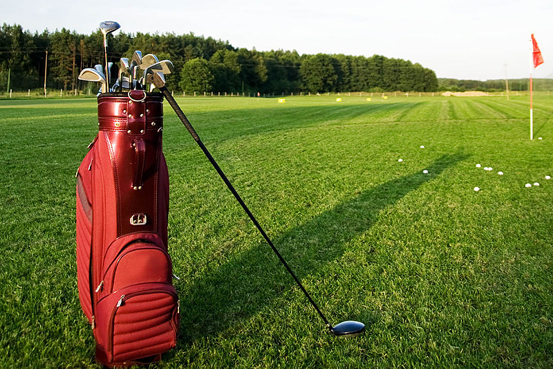 Sac de golf rouge sur un parcours d'entraînement de golf au coucher du soleil, parfait pour les séjours PYR Fuengirola