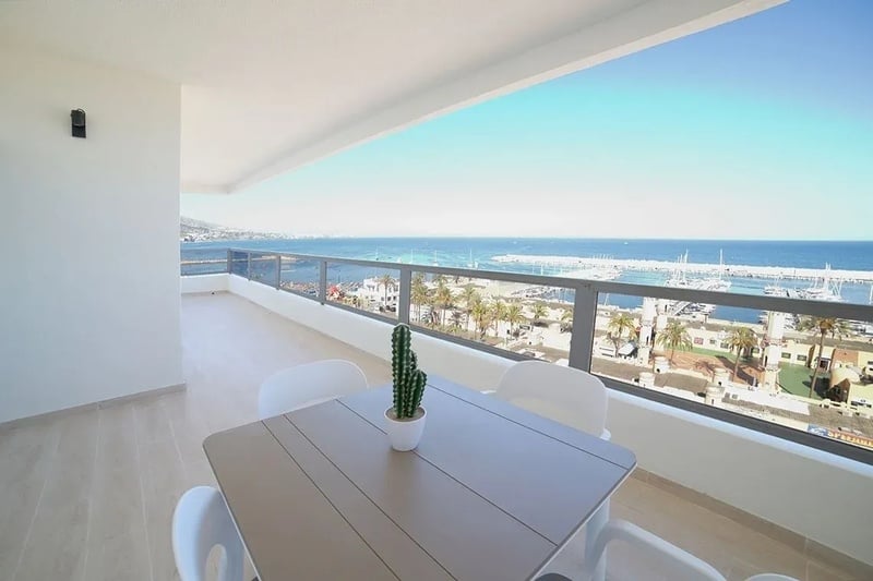 a table and chairs on a balcony overlooking the ocean