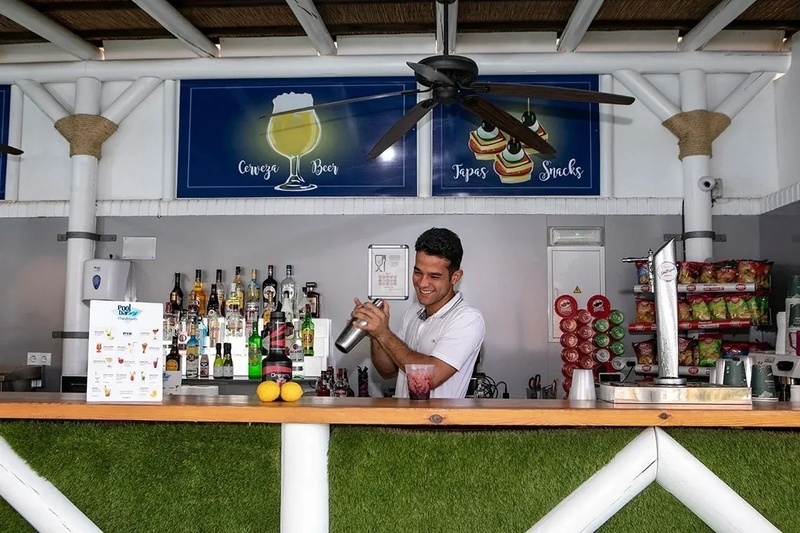 Bar piscine PYR Fuengirola : un serveur prépare des cocktails derrière un bar bien garni.
