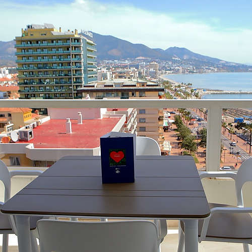 Vista desde balcón de hotel con mesa, sillas y vistas al mar y la ciudad. PYR Fuengirola