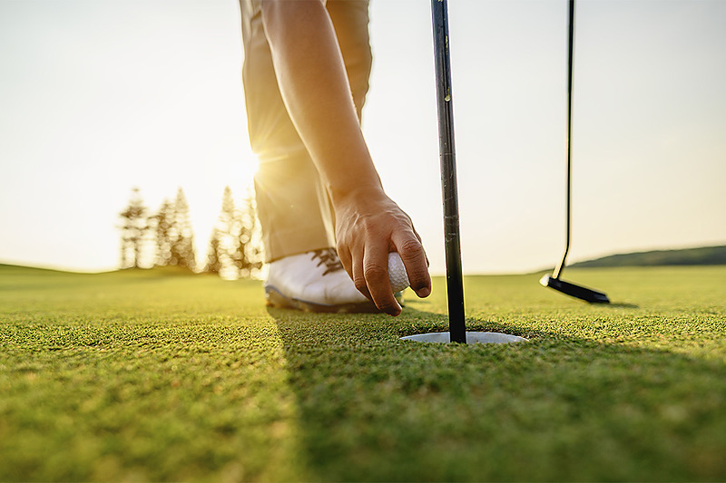 Joueur de golf plaçant la balle dans le trou. PYR Fuengirola sur le green.