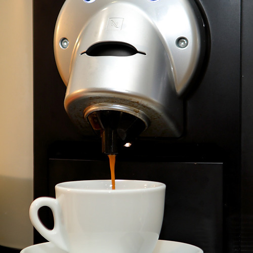 Espresso fresco saliendo de la máquina Nespresso en una taza blanca, perfecto para tu PYR Fuengirola.