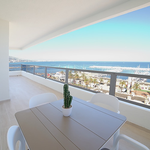 Balcón con vista al mar y puerto deportivo en PYR Fuengirola. Mesa y sillas para disfrutar.