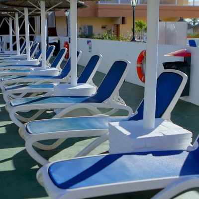 a row of blue and white lounge chairs under umbrellas