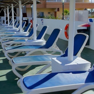 una fila de tumbonas azules y blancas están alineadas alrededor de una piscina